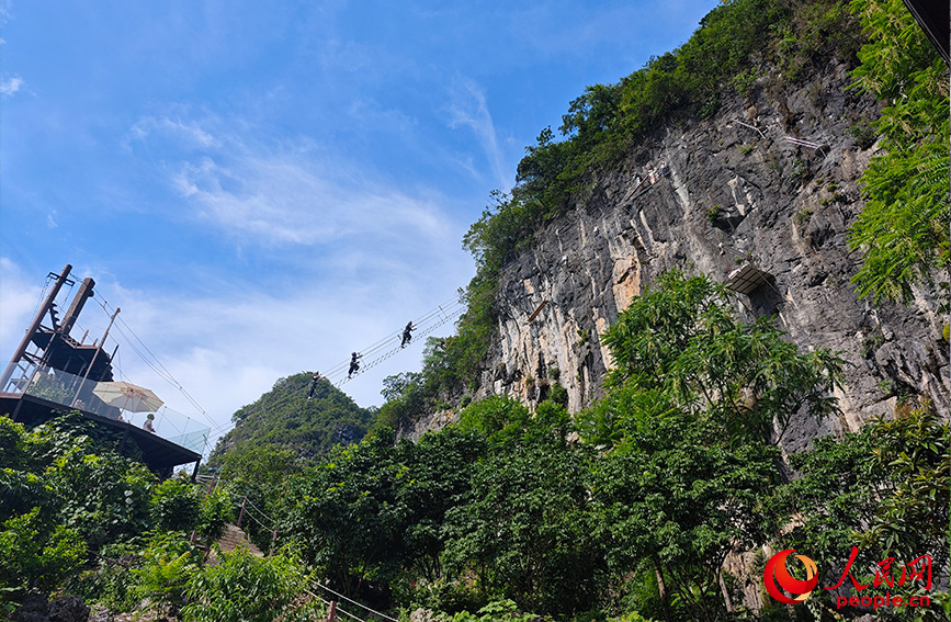 行进中国丨穿梭云端峭壁 解锁桂林山水新视角当游客穿戴好安全设备，爬上通往悬崖峭壁的“天梯”，悬于山间，脚下是美丽的田园风光，清澈的小河蜿蜒流淌，远处是连绵的山峰，共同构成了一幅生机勃勃的山水田园画卷。